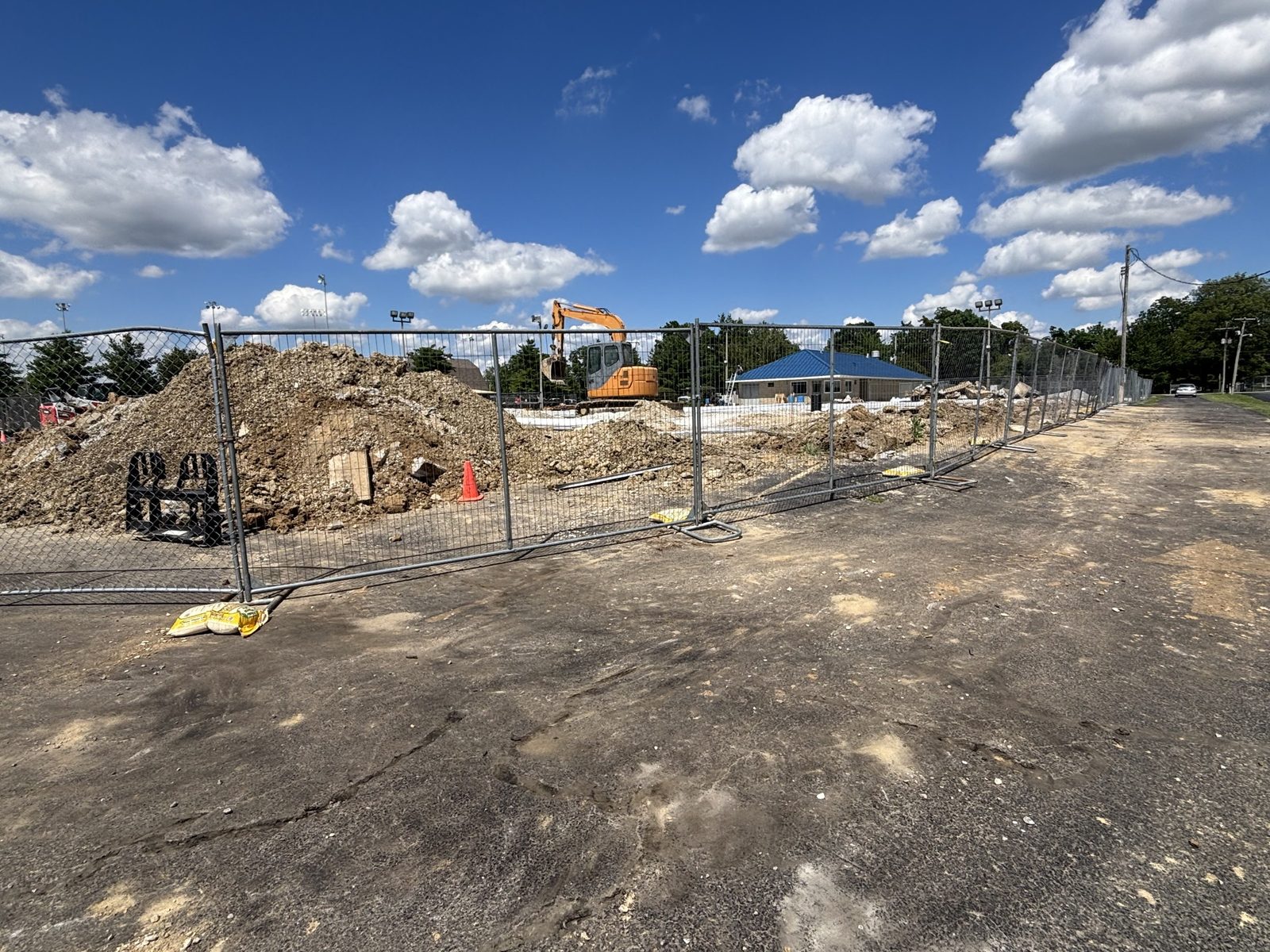 Temporary fence panels around a dirt lot with an excavator