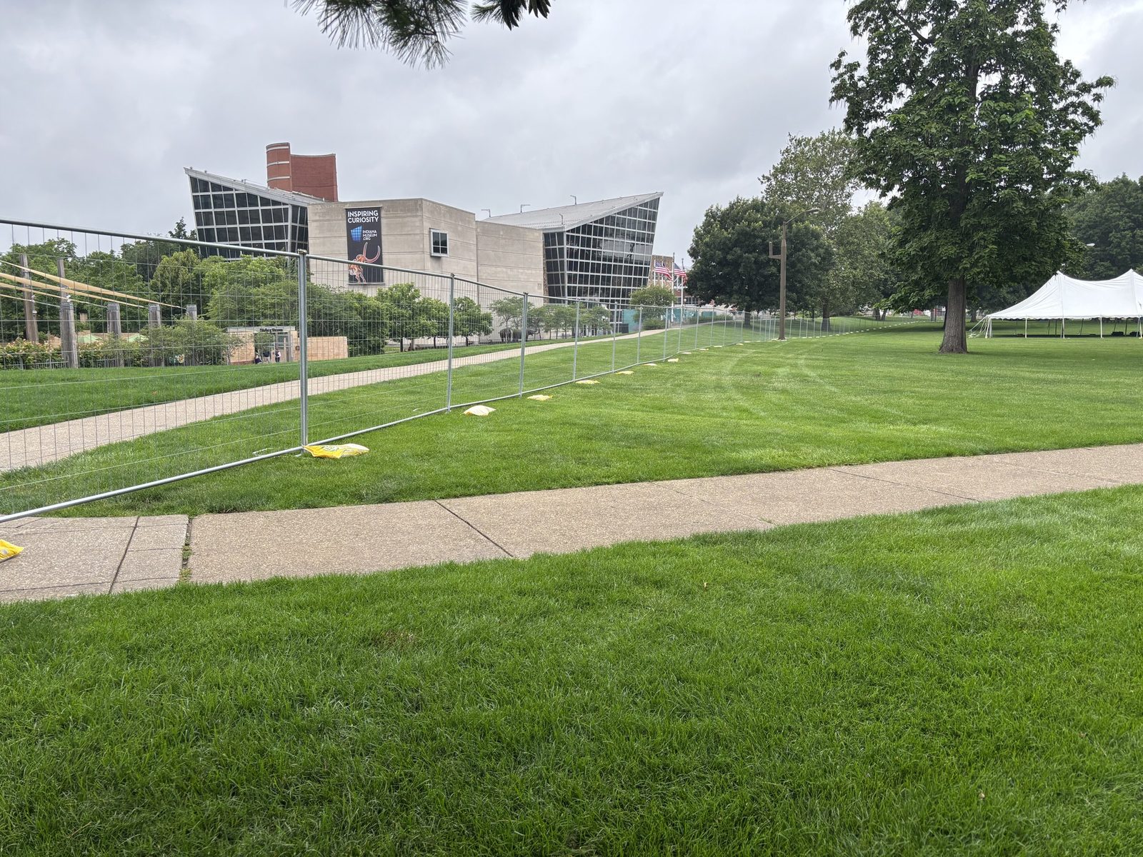 Panel fence on stands across a lawn with event tents in the background