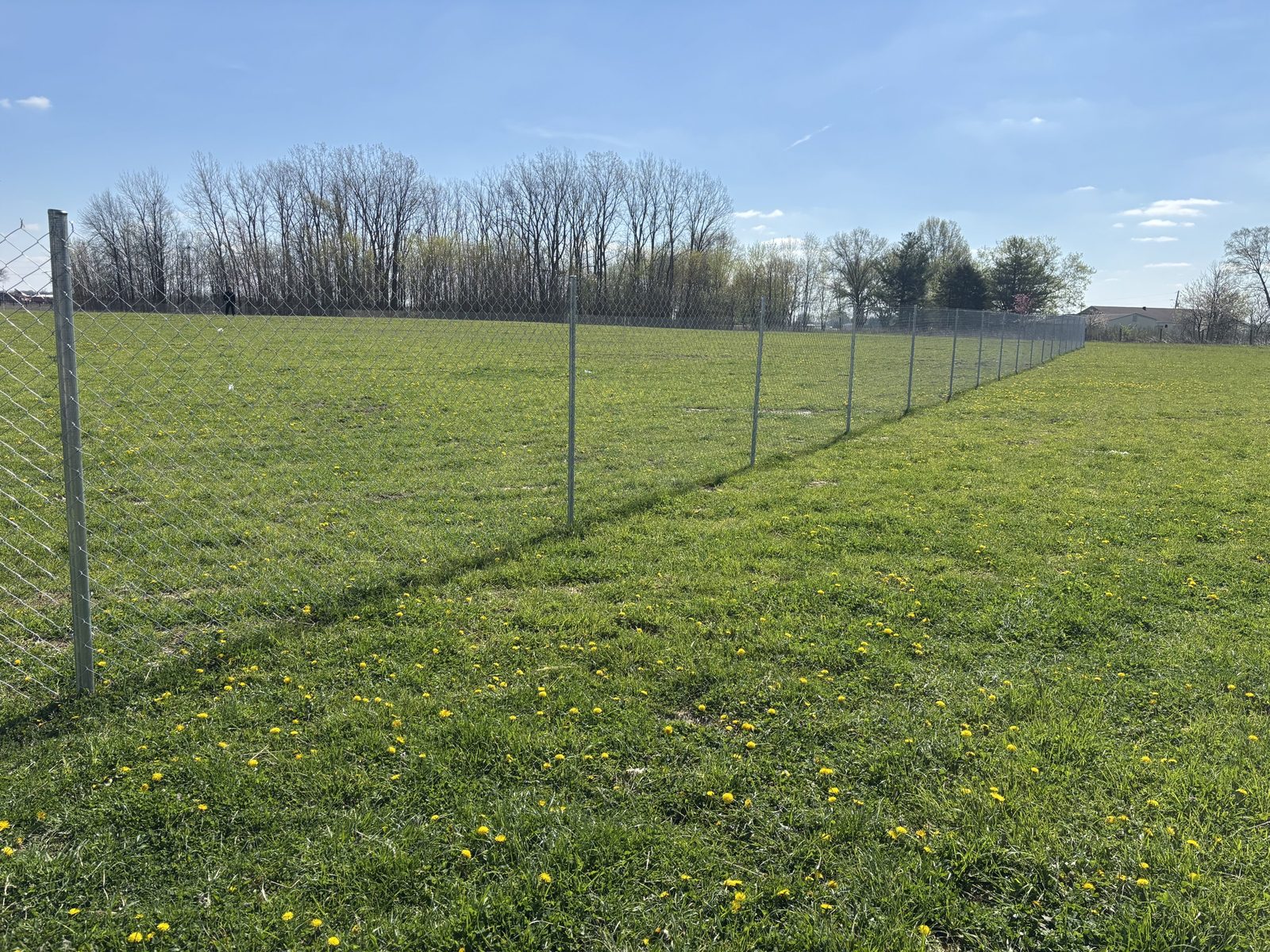 A long straight run of chain link fence across a grass field