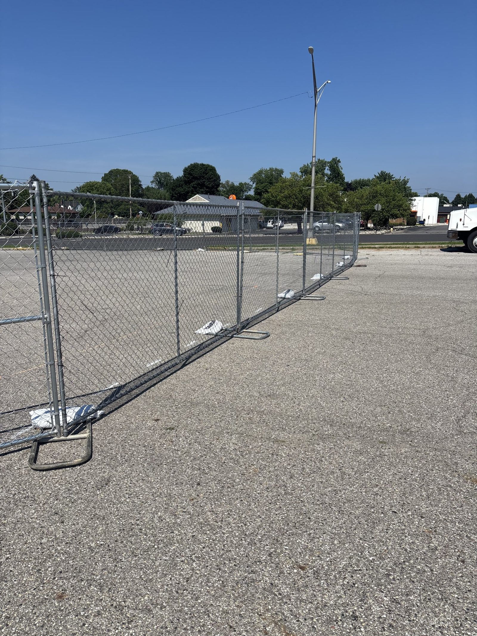 Panel fence on stands across a paved lot