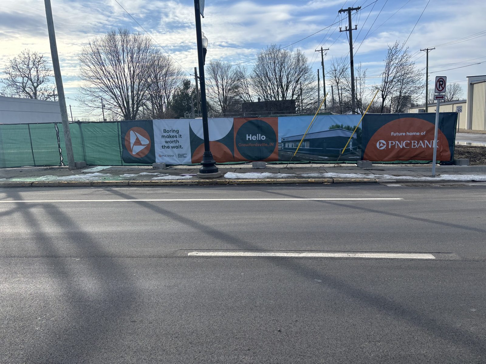 Printed windscreen banners along a fence line beside a city street
