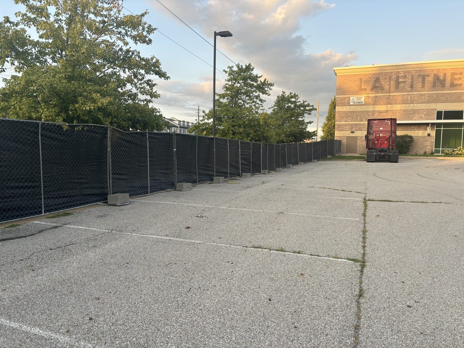 Black windscreen on a fence run along a concrete lot beside a building